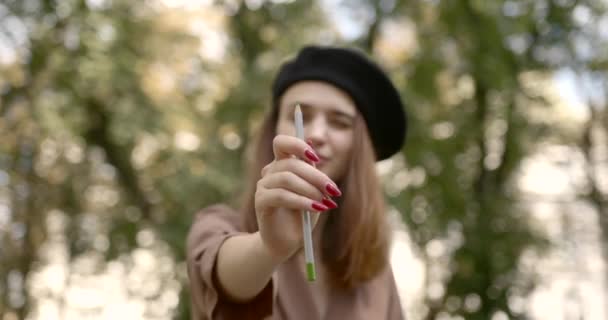 Girl artist holding a green pencil in front of her in the park — Stock Video