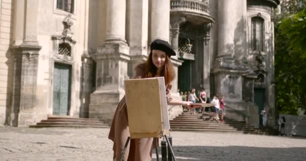 Chica artista delante de un caballete en la plaza — Vídeos de Stock