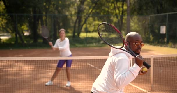Многорасовая молодежь играет в теннис на открытом корте — стоковое видео