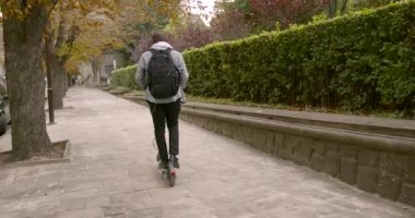 Genç bir adam sokakta elektrikli scooter kullanıyor.