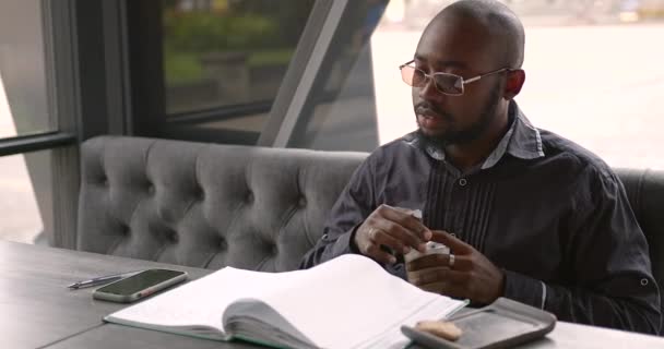 Jovem empresário negro fala ao telefone em um café — Vídeo de Stock