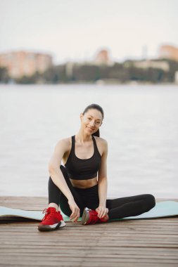 Su kenarında yoga yapan bir kadın.