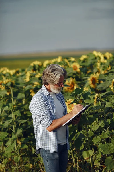 Antiguo granjero en camisa de pie en el campo con cuaderno —  Fotos de Stock