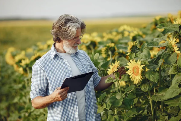 Antiguo granjero en camisa de pie en el campo con cuaderno —  Fotos de Stock