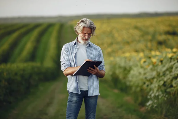 Antiguo granjero en camisa de pie en el campo con cuaderno —  Fotos de Stock