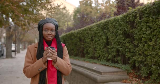 Joven mujer negra calienta sus manos con una taza de café — Vídeos de Stock