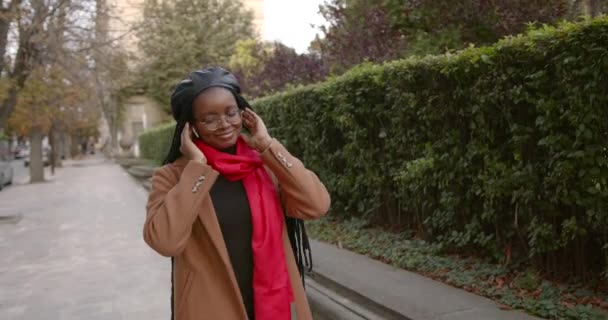 Чорна дівчина посеред вулиці в навушниках — стокове відео