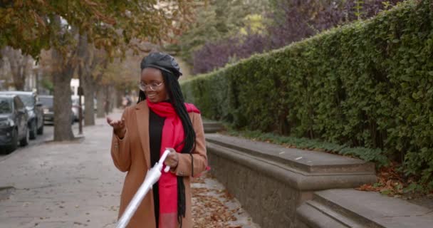 Chica negra con un paraguas en medio de la calle de otoño — Vídeos de Stock