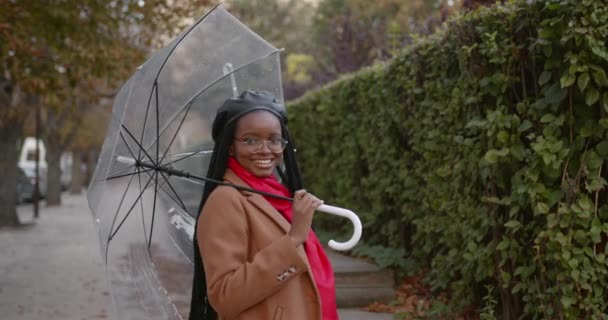 Chica negra con un paraguas en medio de la calle de otoño — Vídeos de Stock