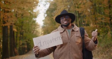 Yol kenarında elinde işaret olan siyah bir otostopçu.