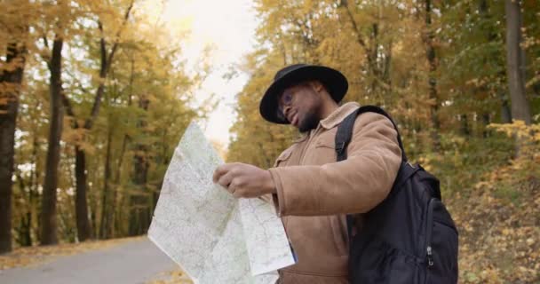 가을 숲에 지도가 있는 젊은 흑인 관광객 — 비디오