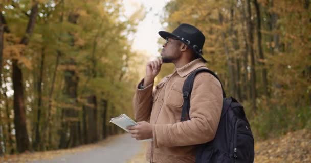 Ένας νεαρός μαύρος πεζοπόρος με χάρτη και σακίδιο. — Αρχείο Βίντεο