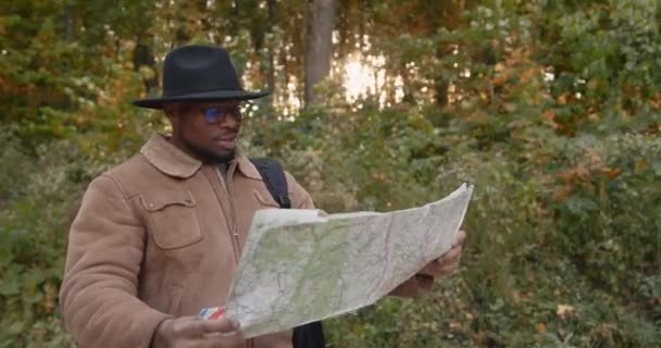 Young black traveler with a map in the wood — Stock Video