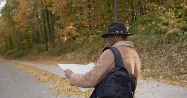 Πίσω όψη νεαρός μαύρος ταξιδιώτης με χάρτη στα χέρια — Αρχείο Βίντεο