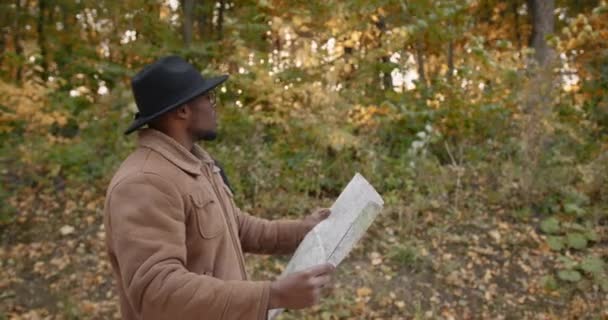 Pelancong hitam muda dengan peta berjalan di hutan — Stok Video