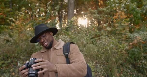 Black traveler with a camera in autumn forest — Stock Video