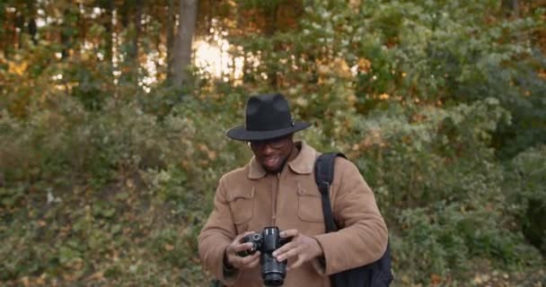 Viajero negro con cámara en bosque otoñal — Vídeos de Stock