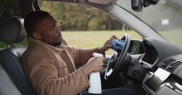 Homme noir assis dans la voiture et nettoyer le volant — Video