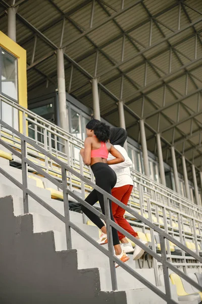 Две черные женщины бегут по лестнице на стадионе — стоковое фото