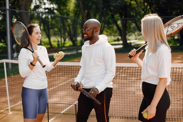 Due donne e allenatore di razza nera al campo da tennis — Foto Stock