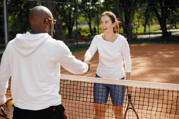 Un homme et une femme serrent la main au court de tennis — Photo