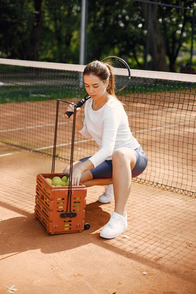 Mujer con raquet y caja de bolas a pie en la cancha — Foto de Stock