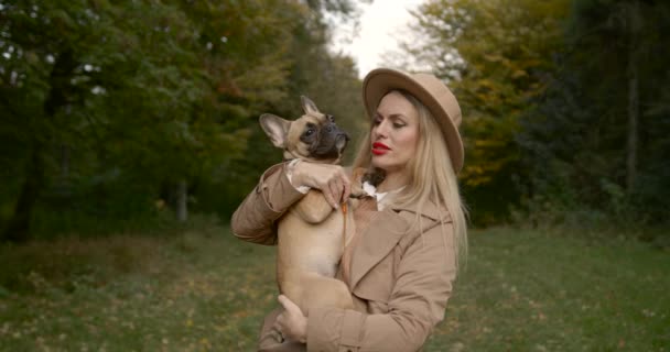 秋の森の中にフランスのブルドッグを持つ女性 — ストック動画