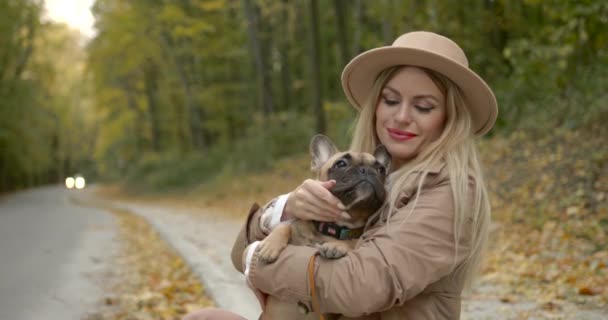 Giovane donna che tiene un cane tra le braccia nel parco autunnale — Video Stock