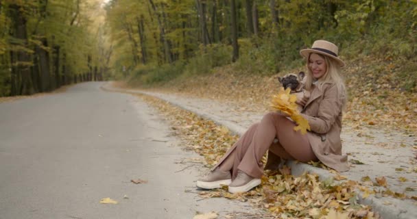 Woman sitting on the side of the alley with a pet in her arms — Stock Video