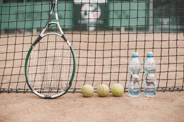Tennisbollar, racket och flaskor vatten på tennisbanan — Stockfoto