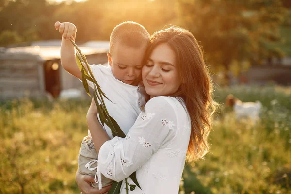 Mãe com o pequeno filho brincando em um campo de verão — Fotografia de Stock