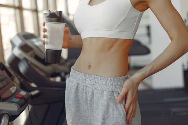 Una hermosa chica de pie en un gimnasio con botella de agua —  Fotos de Stock