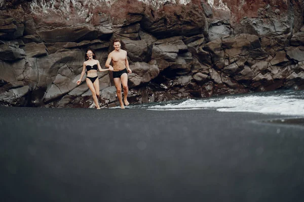 Elegante coppia su una spiaggia vicino a scogli — Foto Stock