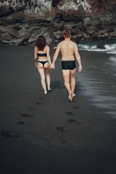 Elegante coppia su una spiaggia vicino a scogli — Foto Stock