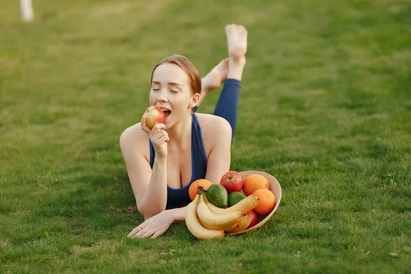 Mulher em um sportwear detém uma fruta — Fotografia de Stock