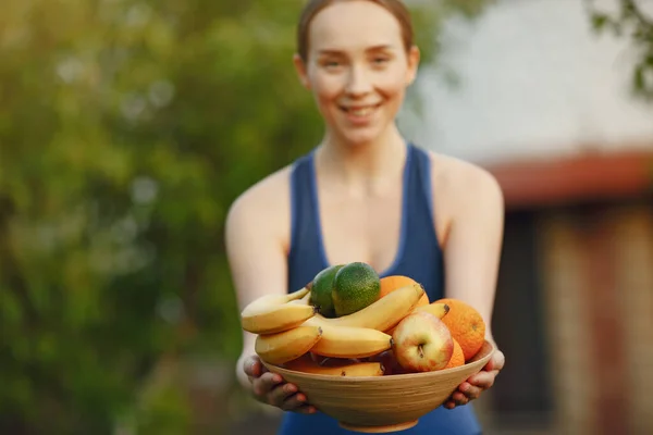 Frau in Sportkleidung hält Frucht in der Hand — Stockfoto