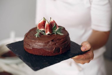 Şef elinde çikolatalı pasta tutuyor..
