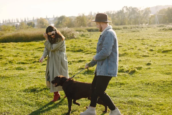 Stijlvol koppel wandelen met een bruine labrador op een natuur — Stockfoto