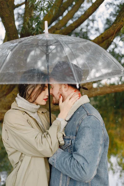 Casal romântico elegante em pé perto do lago sob guarda-chuva transparente — Fotografia de Stock