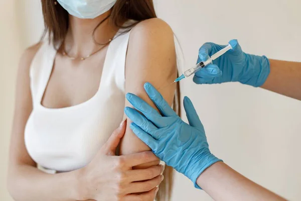 Vrouw met masker die een injectie in haar arm krijgt — Stockfoto