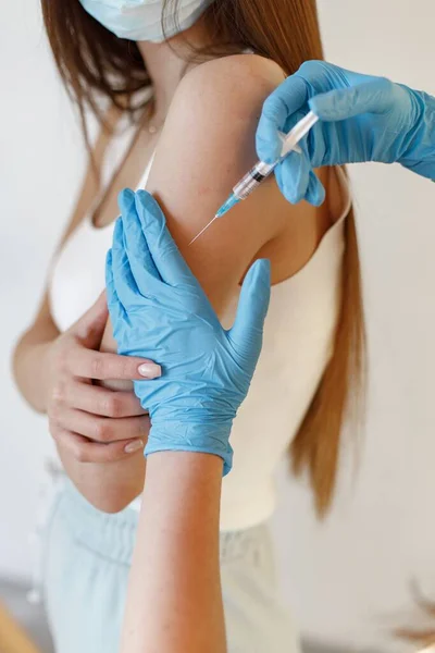 Vrouw met masker die een injectie in haar arm krijgt — Stockfoto