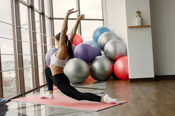 Jimnastik salonundaki sporcu kız esnemiş.