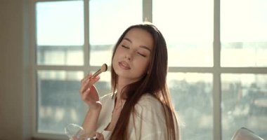 Evde yüz masajı için yeşim yüz silindiri kullanan kadın.