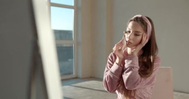 Evde yüz masajı için yeşim yüz silindiri kullanan kadın.