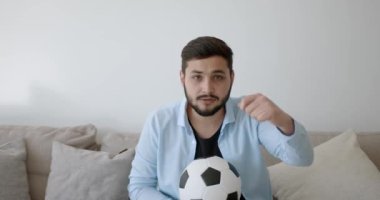 Genç bir Hint futbol fanatiği evde televizyon izliyor.