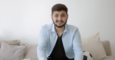 Genç bir Hint futbol fanatiği evde televizyon izliyor.