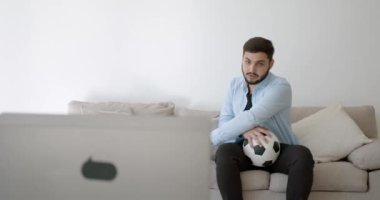 Genç bir Hint futbol fanatiği evde televizyon izliyor.