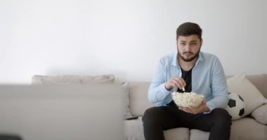 Genç bir Hint futbol fanatiği evde televizyon izliyor.