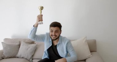 Genç bir Hint futbol fanatiği evde televizyon izliyor.