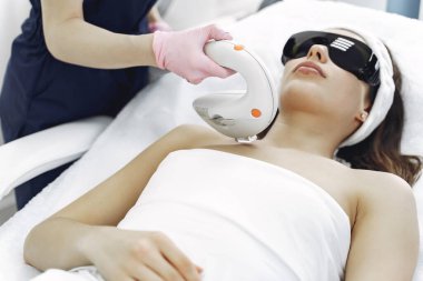 Kozmetoloji stüdyosunda lazer tüy temizleme üzerine çalışan bir kadın.